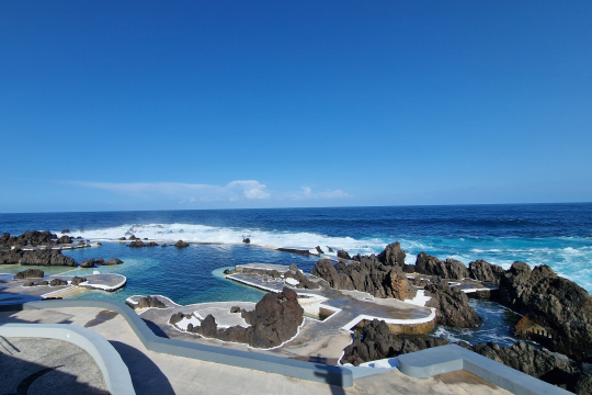 Die berühmten Naturpools von Madeira, geformte Becken aus Stein mit türkisblauem Wasser, dahinter das offene Meer